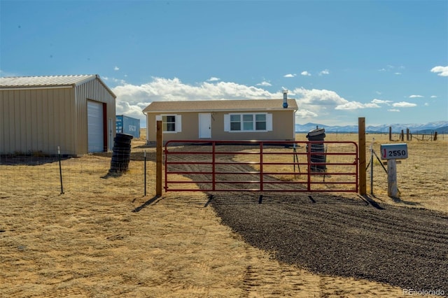 exterior space with a rural view, fence, a mountain view, and an outbuilding