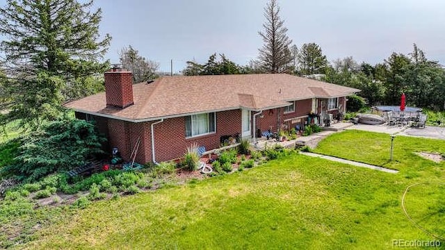 1614 N Manila Rd, Bennett, CO 80102 - view of front of home with a chimney, a front lawn, brick siding, and a patio