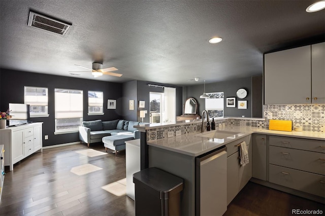 kitchen with dishwasher, decorative backsplash, sink, kitchen peninsula, and dark hardwood / wood-style floors