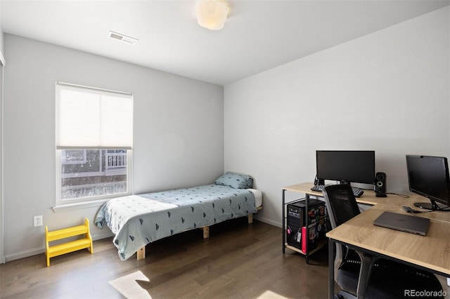 bedroom with baseboards, visible vents, and wood finished floors