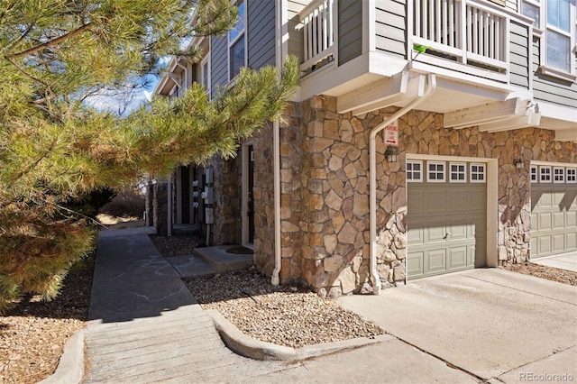 view of side of home featuring an attached garage, stone siding, and driveway