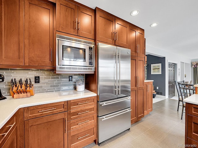 kitchen with decorative backsplash, appliances with stainless steel finishes, brown cabinets, light countertops, and recessed lighting