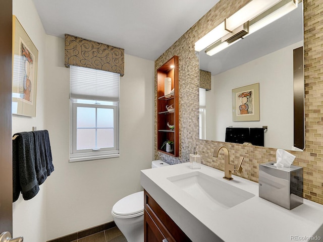 bathroom with baseboards, decorative backsplash, toilet, and vanity