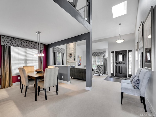 dining space with a skylight, baseboards, a high ceiling, and light colored carpet