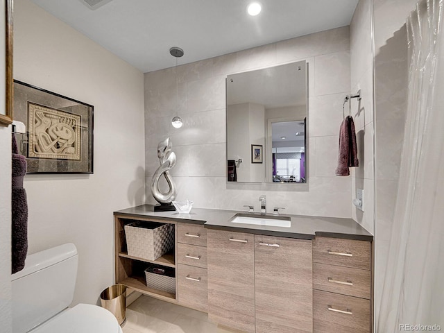 bathroom featuring vanity, tasteful backsplash, toilet, and tile walls