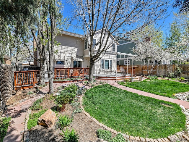 back of house featuring a lawn, a wooden deck, and a fenced backyard