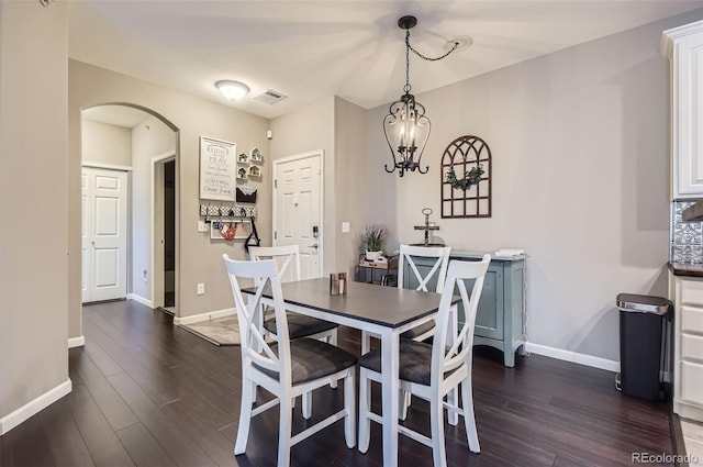 dining area featuring arched walkways, baseboards, dark wood finished floors, and visible vents