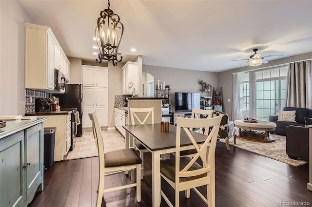 dining room with arched walkways, recessed lighting, dark wood-style floors, and ceiling fan with notable chandelier