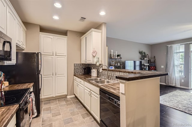 kitchen with visible vents, dark countertops, a sink, black appliances, and a peninsula