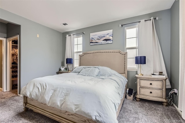bedroom featuring visible vents, multiple windows, and dark colored carpet
