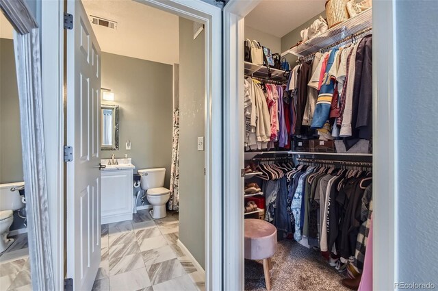 walk in closet with visible vents and marble finish floor