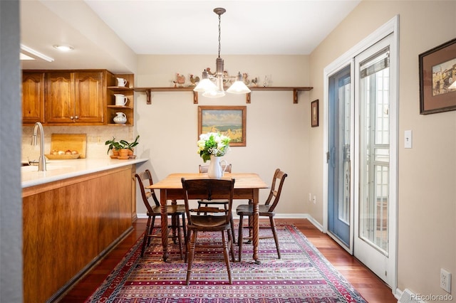 dining room with a notable chandelier, dark wood-type flooring, and sink