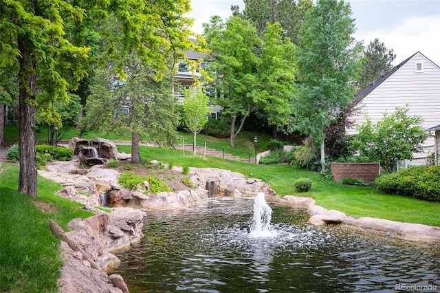 view of property's community with a lawn and a water view