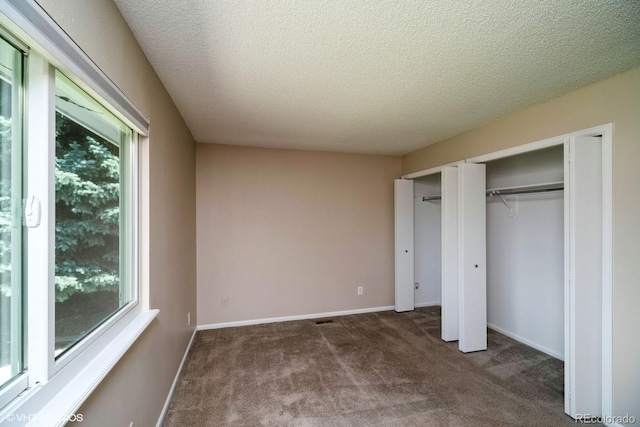 7325 S Houstoun Waring Cir, Littleton, CO 80120 - unfurnished bedroom featuring multiple windows, two closets, carpet flooring, and a textured ceiling