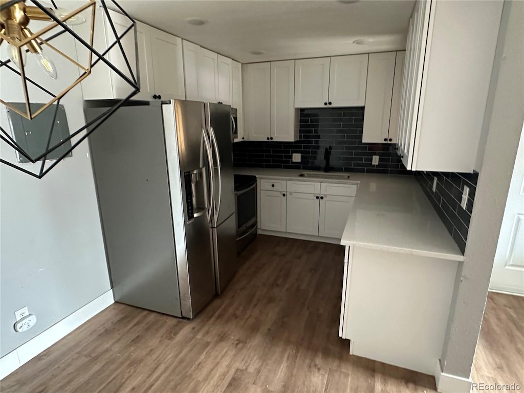 kitchen with white cabinetry, stove, sink, and stainless steel fridge