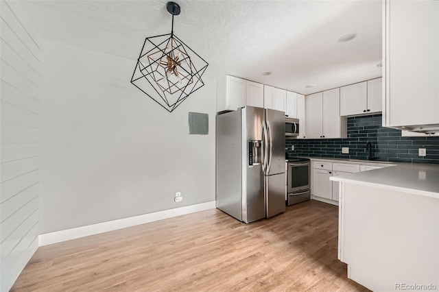 kitchen with stainless steel appliances, tasteful backsplash, hanging light fixtures, and white cabinets