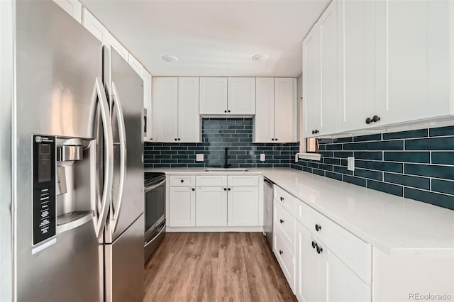 kitchen featuring sink, light hardwood / wood-style flooring, white cabinets, stainless steel appliances, and backsplash