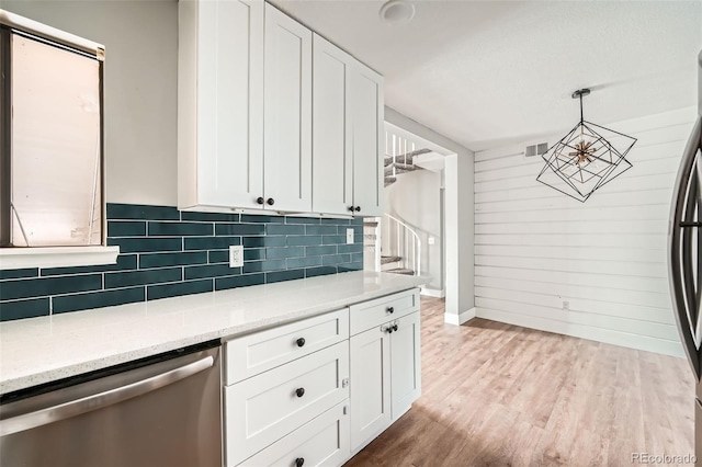 kitchen with decorative light fixtures, white cabinets, stainless steel appliances, light stone countertops, and light wood-type flooring