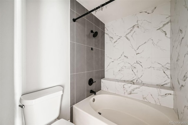 bathroom featuring tiled shower / bath combo and toilet