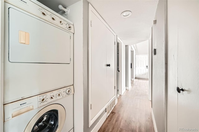 washroom with stacked washer and dryer and wood-type flooring