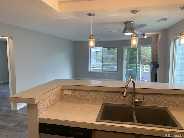 kitchen featuring dishwasher, a textured ceiling, a sink, and visible vents