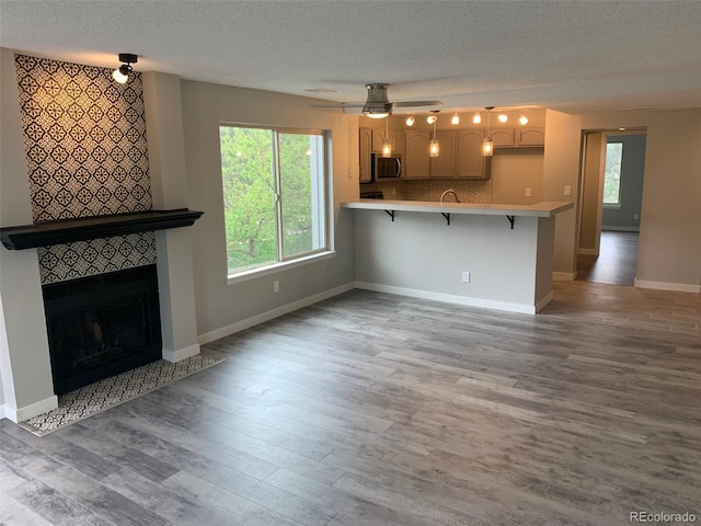 unfurnished living room featuring a textured ceiling, a fireplace, wood finished floors, and a wealth of natural light