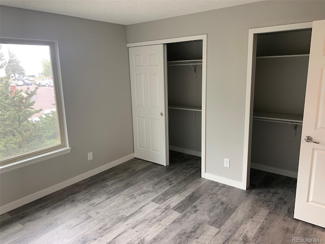 unfurnished bedroom featuring a textured ceiling, wood finished floors, and baseboards