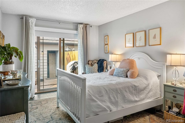 bedroom featuring a textured ceiling, access to outside, and hardwood / wood-style floors