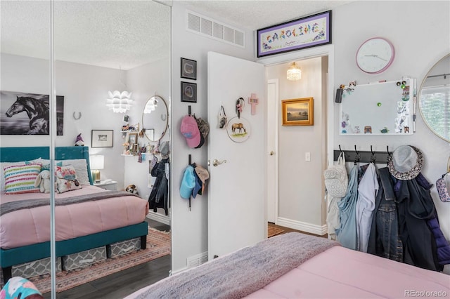 bedroom with a closet, a textured ceiling, and hardwood / wood-style floors