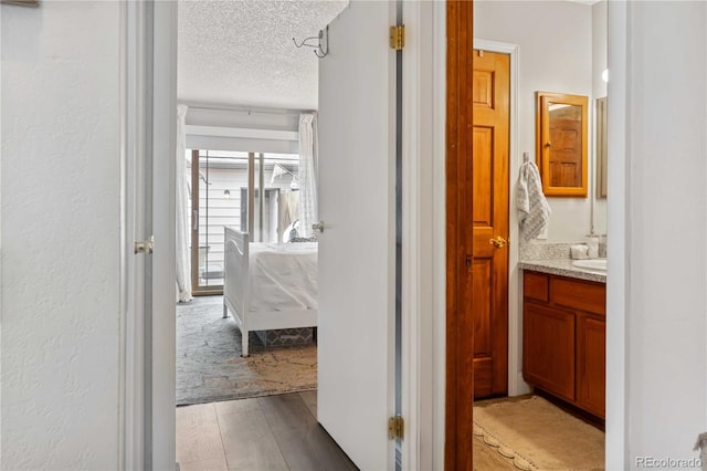 hallway featuring sink, light hardwood / wood-style flooring, and a textured ceiling