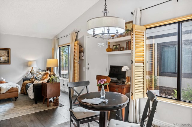 dining space featuring lofted ceiling, wood-type flooring, and an inviting chandelier