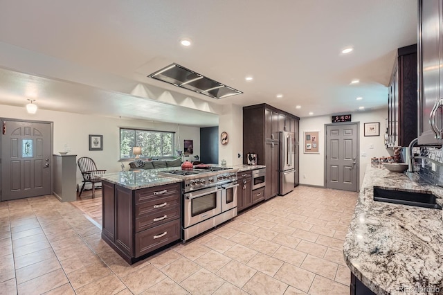 7875 W 21st Ave, Lakewood, CO 80214 - kitchen featuring high end appliances, dark brown cabinets, range hood, light stone countertops, and recessed lighting