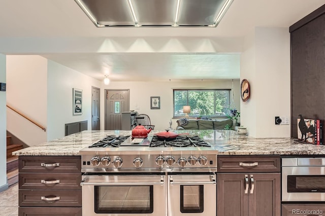 7875 W 21st Ave, Lakewood, CO 80214 - kitchen featuring stainless steel appliances, dark brown cabinetry, light stone countertops, a peninsula, and open floor plan