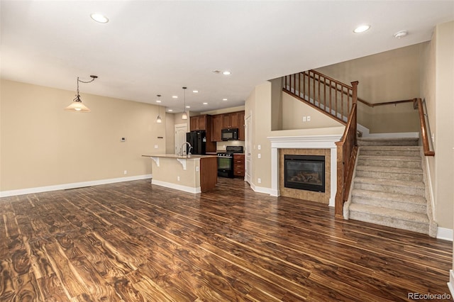 unfurnished living room with baseboards, recessed lighting, dark wood-style flooring, a sink, and stairs