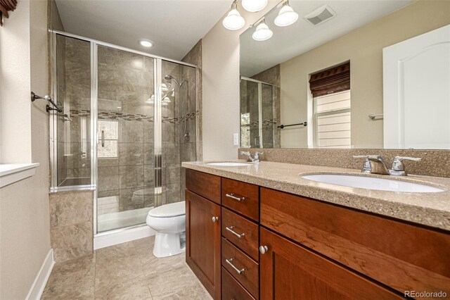 bathroom with tile patterned floors, vanity, toilet, and a shower with shower door