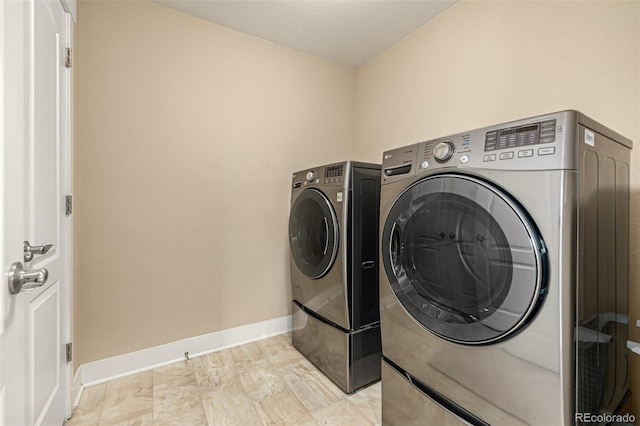 clothes washing area featuring baseboards, laundry area, and washing machine and clothes dryer