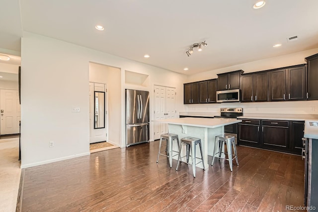 12981 E 108th Way, Commerce City, CO 80022 - kitchen featuring stainless steel appliances, a kitchen bar, dark wood-type flooring, light countertops, and a center island