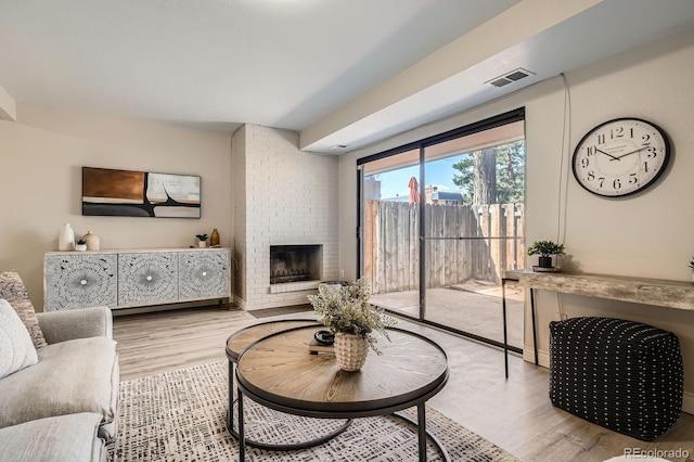 living area with wood finished floors, a brick fireplace, and baseboards