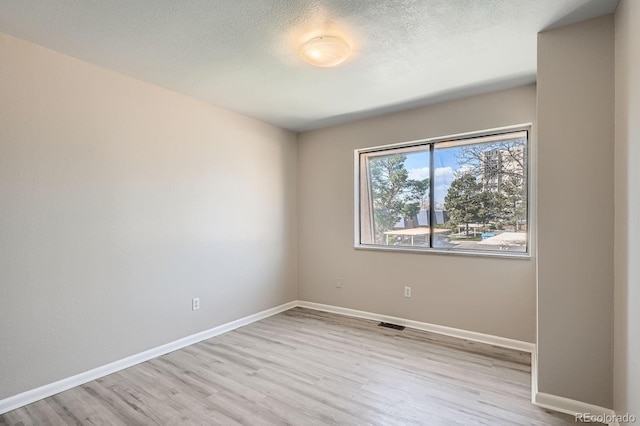 unfurnished room with wood finished floors, baseboards, and a textured ceiling