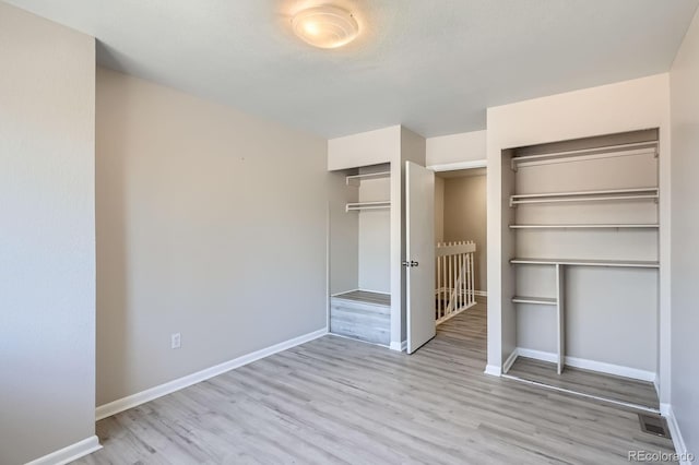 unfurnished bedroom with wood finished floors, baseboards, and multiple closets