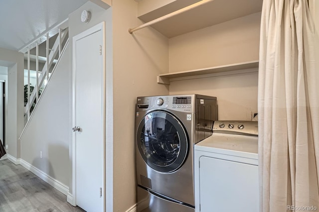 laundry area featuring washer and dryer, light wood-type flooring, and baseboards