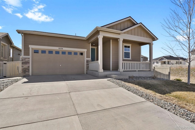 view of front of house with board and batten siding, fence, concrete driveway, covered porch, and an attached garage