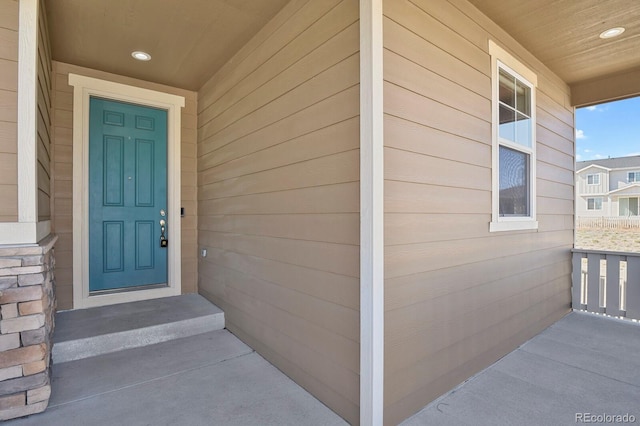 view of exterior entry with stone siding and covered porch