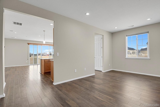 spare room featuring dark wood finished floors, baseboards, and visible vents