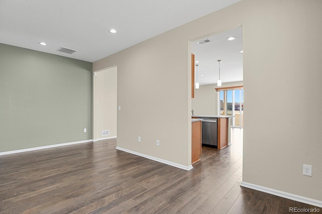 unfurnished room featuring visible vents, dark wood-type flooring, and baseboards