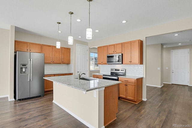 kitchen with dark wood-style floors, baseboards, an island with sink, a sink, and stainless steel appliances