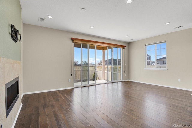 unfurnished living room featuring a glass covered fireplace, dark wood-type flooring, baseboards, and visible vents