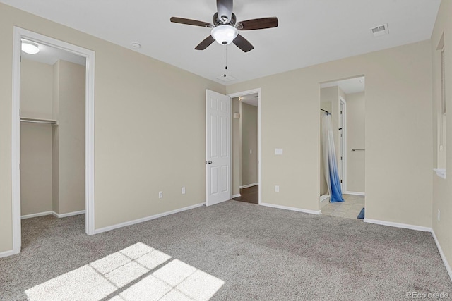 unfurnished bedroom with visible vents, a walk in closet, baseboards, carpet, and ensuite bathroom