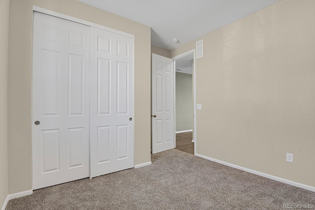 unfurnished bedroom with a closet, baseboards, carpet, and visible vents