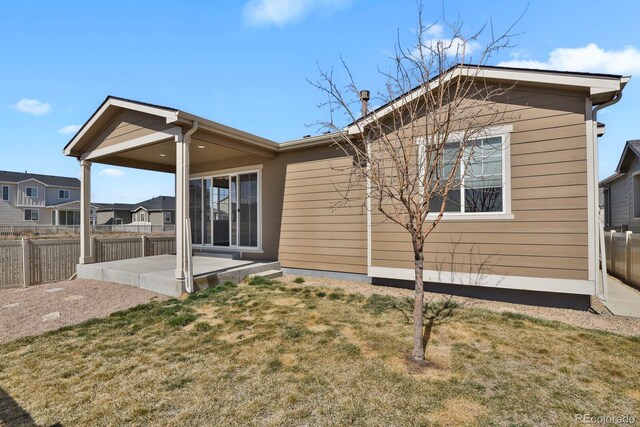 back of property featuring a patio area, a lawn, and fence